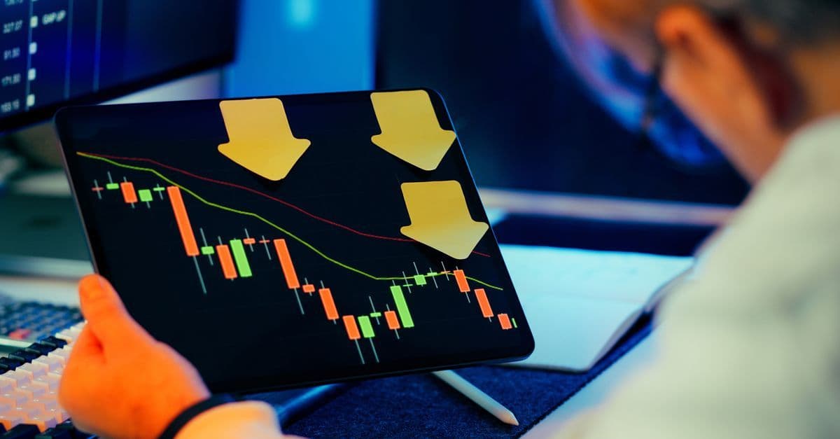 Geschäftsmann analysiert auf einem Tablet einen fallenden Börsenchart, angespannte Finanzlage sichtbar