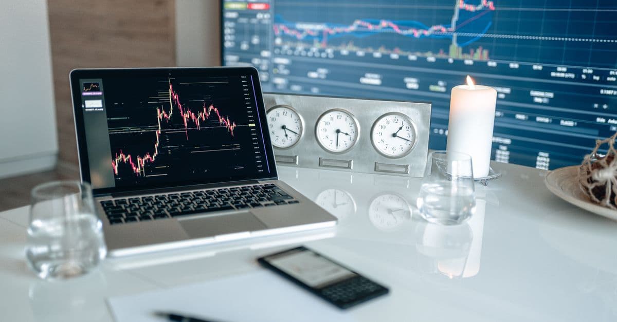 Moderner Arbeitsplatz mit Finanzdiagrammen und mehreren Uhren auf weißem Tisch