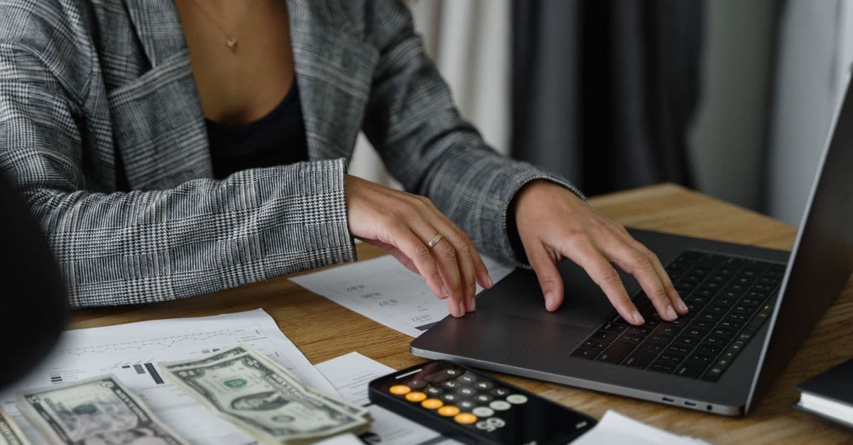 Geschäftsfrau bei der Finanzplanung mit Bargeld und Taschenrechner am Schreibtisch