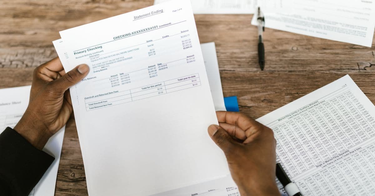 Hände halten Finanzunterlagen zur Steuererklärung und Analyse.