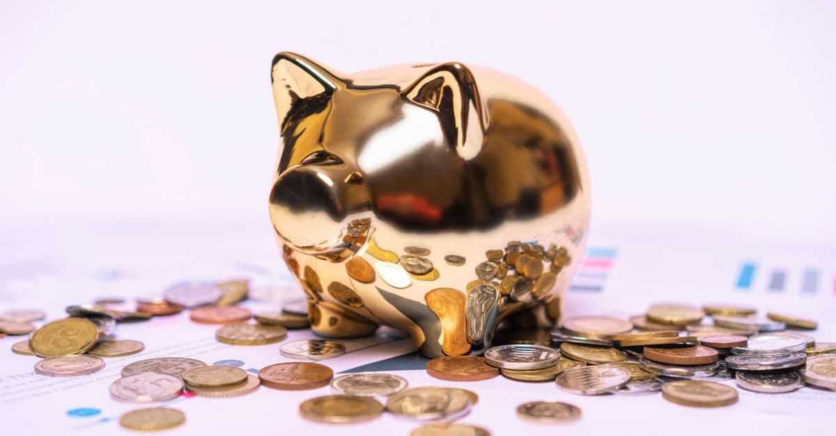 Goldenes Sparschwein auf Finanzdokumenten mit verstreuten Münzen