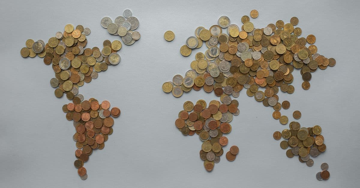 Weltkarte aus verschiedenen Münzen auf grauem Hintergrund, als Darstellung globaler Finanzmärkte